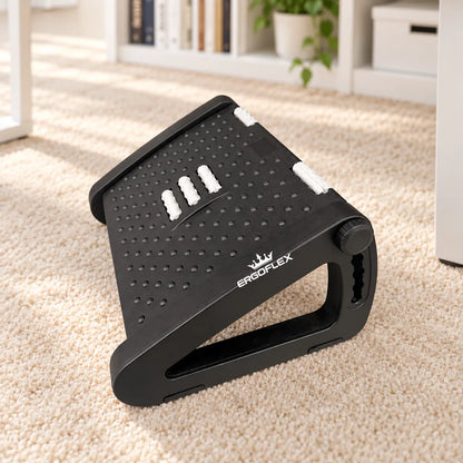 ErgoFlex black adjustable footrest with white crown logo in a home office on a neutral carpet